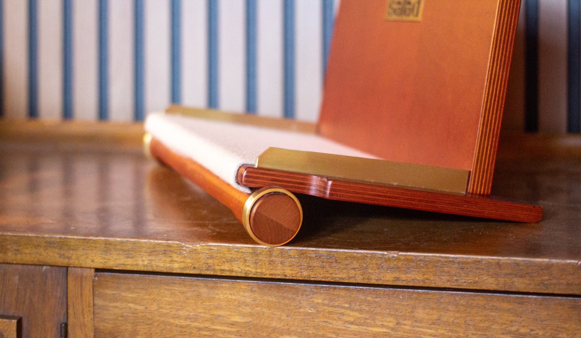 Low-angle detail shot of the Salad Flip Vinyl Rack showing birch ply lamination layers, brass end plates, and felt lining
